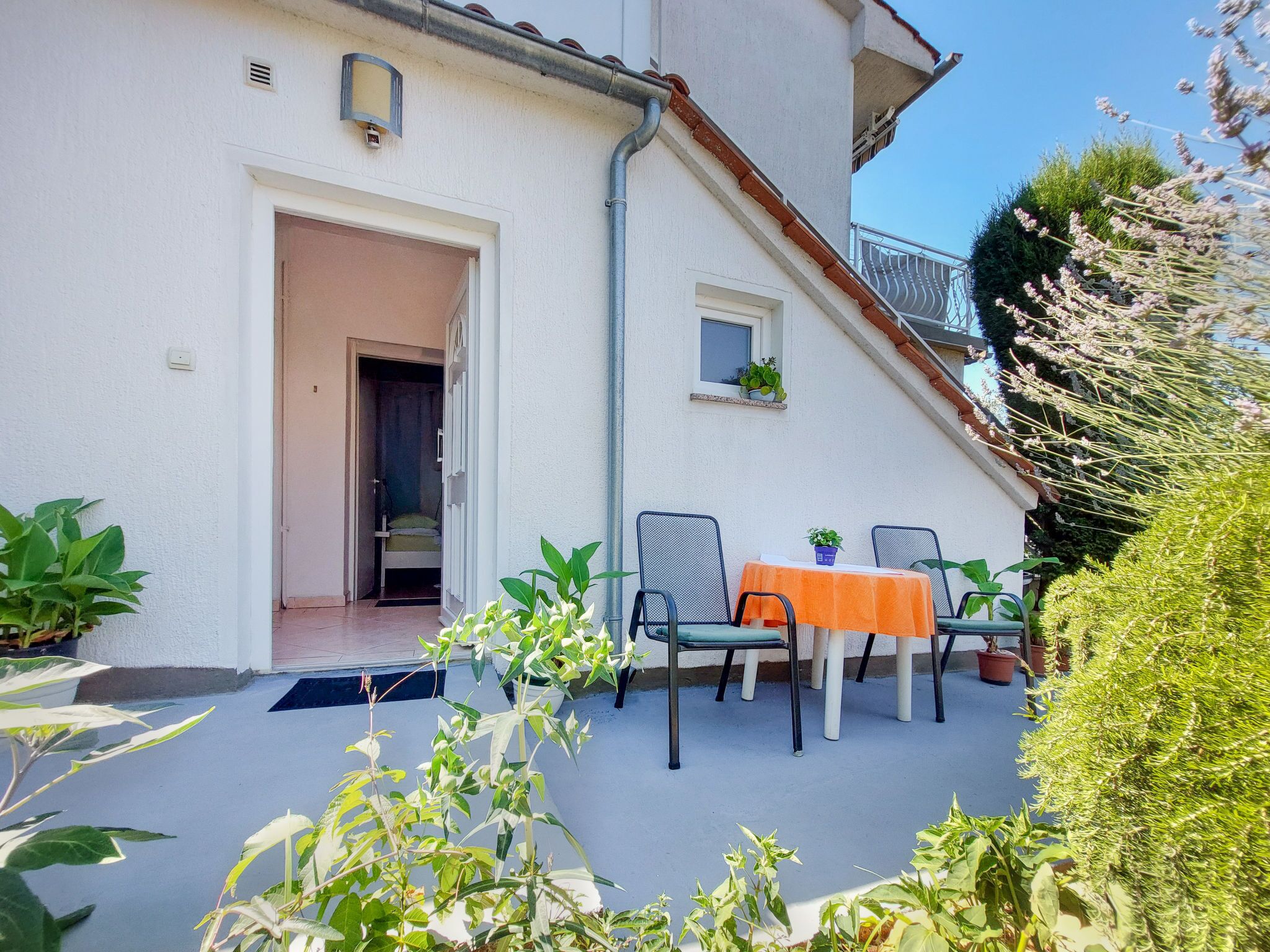 A patio with a table and chairs, a small window, and potted plants.