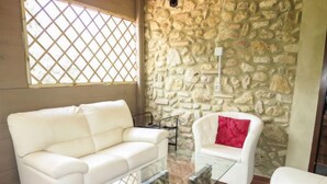 A living room with a white sofa, a glass coffee table, and a stone wall. - Villa Sofia by Interhome (Volterra)