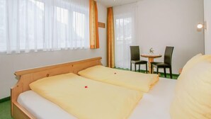 A hotel room with two beds, a small table with chairs, and large windows with sheer curtains. - La Luna by Interhome (Kappl)