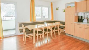 A modern kitchen with wooden cabinets, a dining table with chairs, and a built-in bench. - La Luna by Interhome (Kappl)