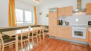 A modern kitchen with wooden cabinets, a dining table with chairs, and a window with curtains. - La Luna by Interhome (Kappl)