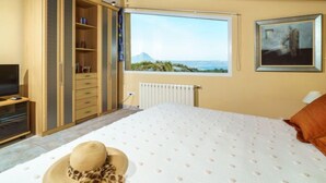 A bedroom with a bed, a wardrobe, a TV, a window with a view, and a radiator. - Bellevue by Interhome (Jávea)