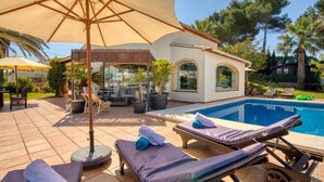 A poolside area with lounge chairs, a covered seating area, and a pool. - Bellevue by Interhome (Jávea)