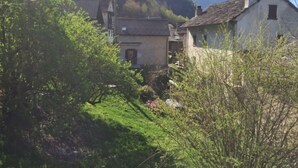 Uma aldeia rural com casas tradicionais, rodeada por vegetação exuberante e montanhas ao fundo.