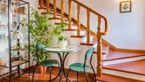 A staircase with wooden balusters, a glass display unit with various items, and a round table with chairs. - Il Colombaino by Interhome (Florence)