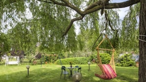 A garden with a swing set, a hanging chair, and a table with chairs. - Il Colombaino by Interhome (Florence)
