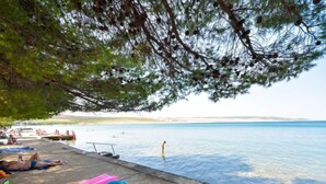 A beachside area with lounge chairs and inflatable toys, a swimming pool, and a clear view of the sea. - Vacation home Dada by Interhome (Rovanjska)