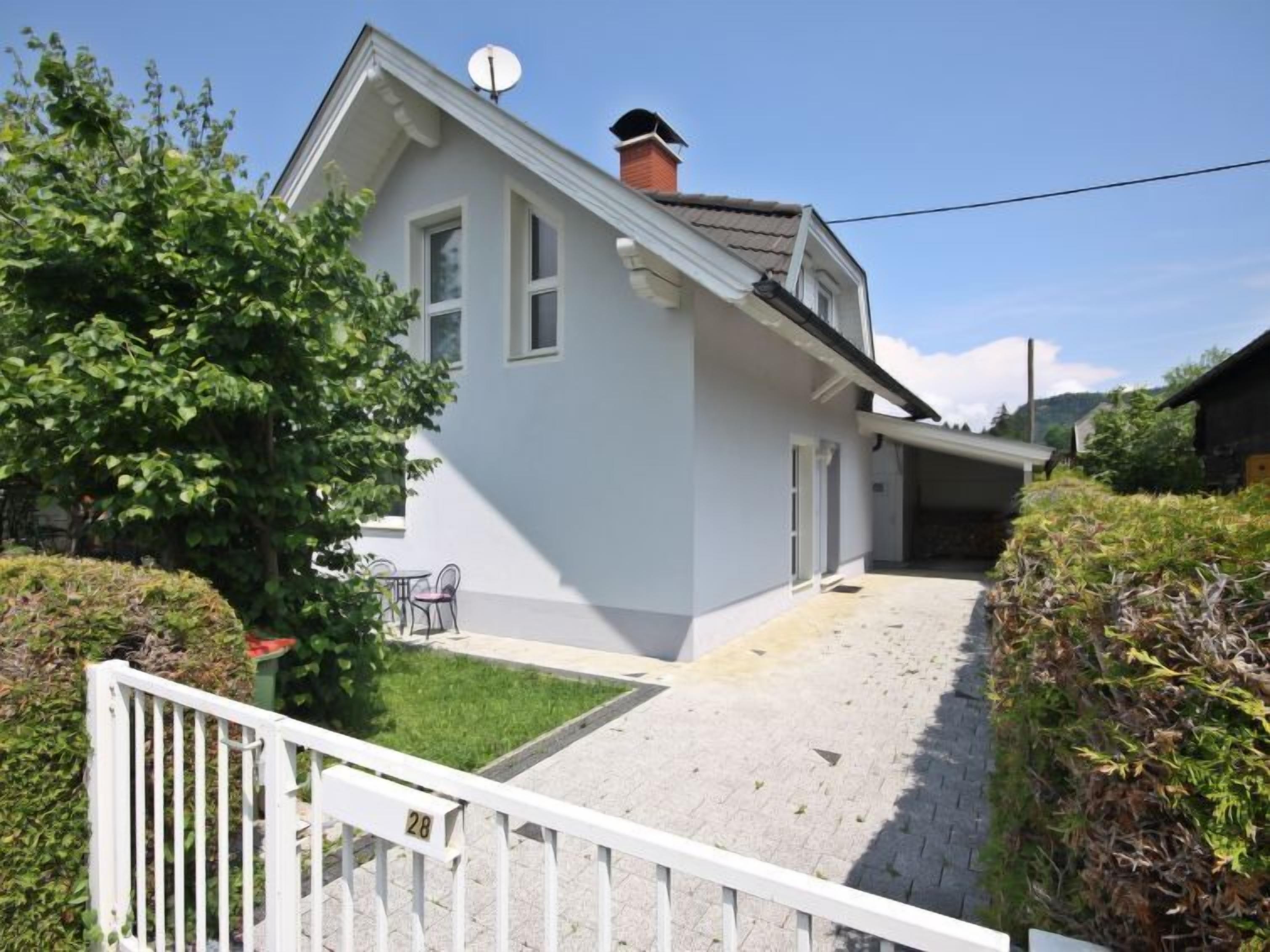 A two-story house with a sloped roof, a satellite dish, and a small front yard with a paved driveway.