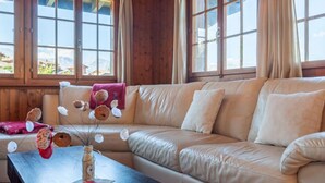 A cozy room with a leather sofa, a wooden coffee table, and a vase with dried flowers. - Mustela by Interhome (Nendaz)