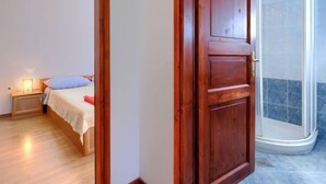 A bedroom with a wooden door, a bed with a blue pillow, and a nightstand with a lamp. - Apartment  Ana by Interhome (Porec/Jehnici)