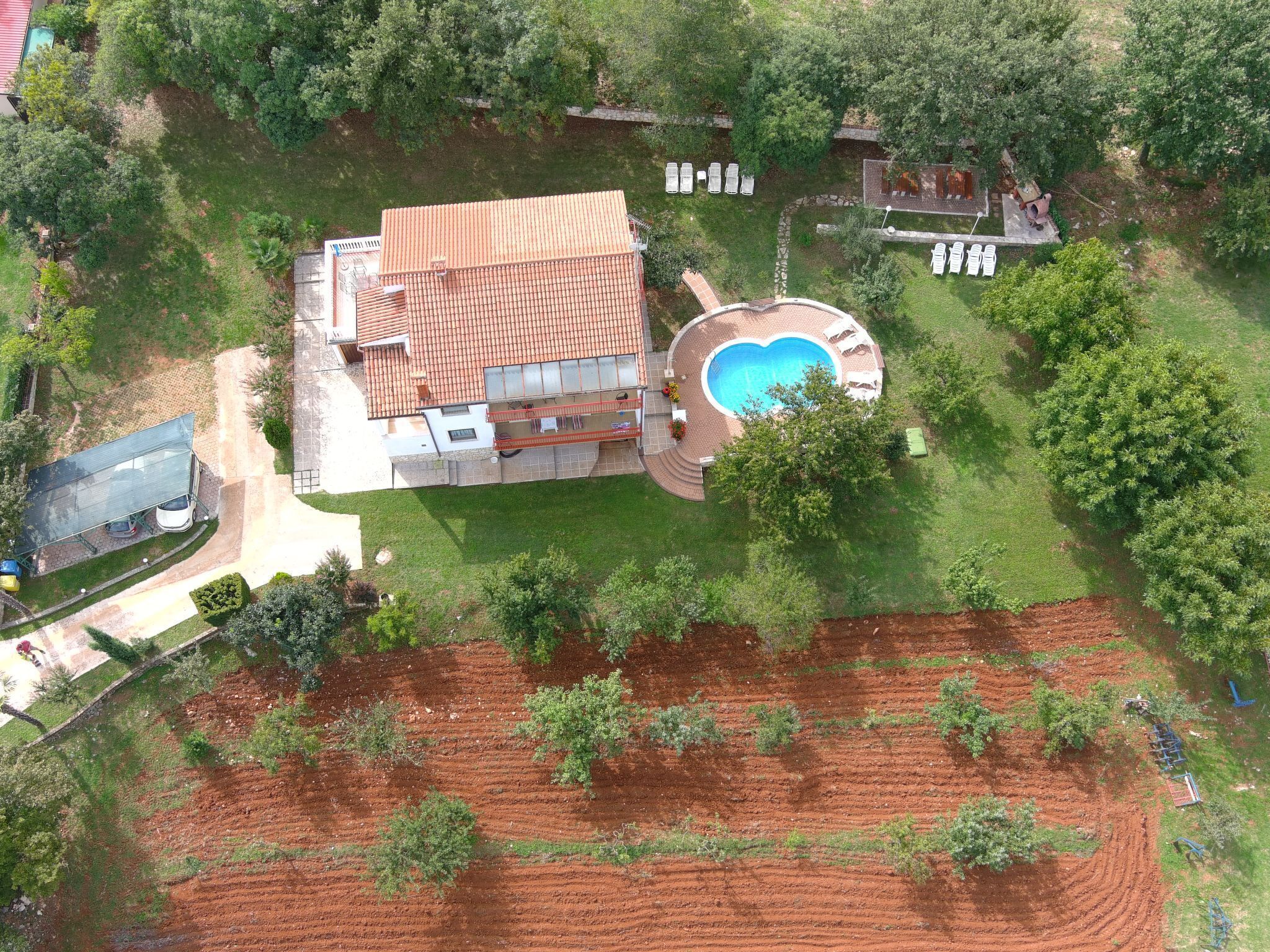 Vue aérienne d’une maison avec une piscine, une terrasse et une cour clôturée.