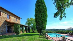 A stone house with a swimming pool and a well-maintained lawn.