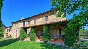 A stone building with a tiled roof, a well-maintained lawn, and potted plants.