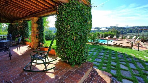 A covered patio with a brick floor, a pool, and a view of the countryside.