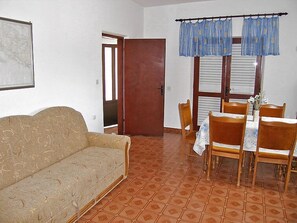 A room with a sofa, dining table with chairs, a window with blinds, and a door. - Vacation home Katica by Interhome (Trstenik/Dingač)