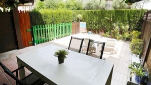 Een terras met een tafel en stoelen, omringd door een houten hek en diverse planten.