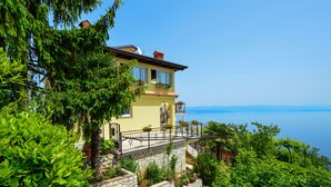 A two-story house with a stone foundation, a balcony with a metal railing, and a view of the sea. - Apartment Laurus by Interhome (Lovran/Tuliševica)