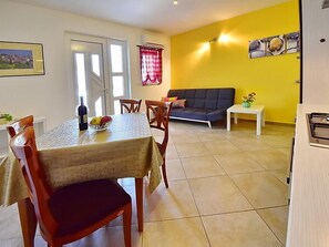 A dining area with a table, chairs, and a sofa in a room with yellow walls and tiled flooring. - Apartment Laurus by Interhome (Lovran/Tuliševica)