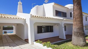 Una casa moderna de dos pisos con techo de tejas, piscina y un jardín cuidado.