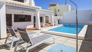 Un área de piscina con sillones de descanso, una mesita y una fuente de agua.