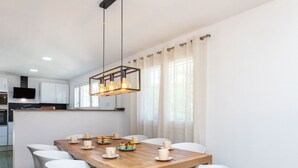Une cuisine moderne avec des meubles blancs, une table à manger en bois et des chaises blanches.