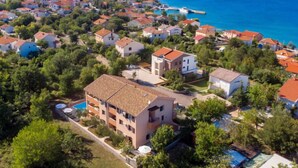 An aerial view of a coastal residential area with houses, a swimming pool, and a view of the sea.