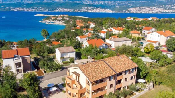 A coastal residential area with houses, a swimming pool, and a view of the sea and mountains.