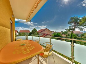 A balcony with a table and chairs, overlooking a residential area with houses and trees.