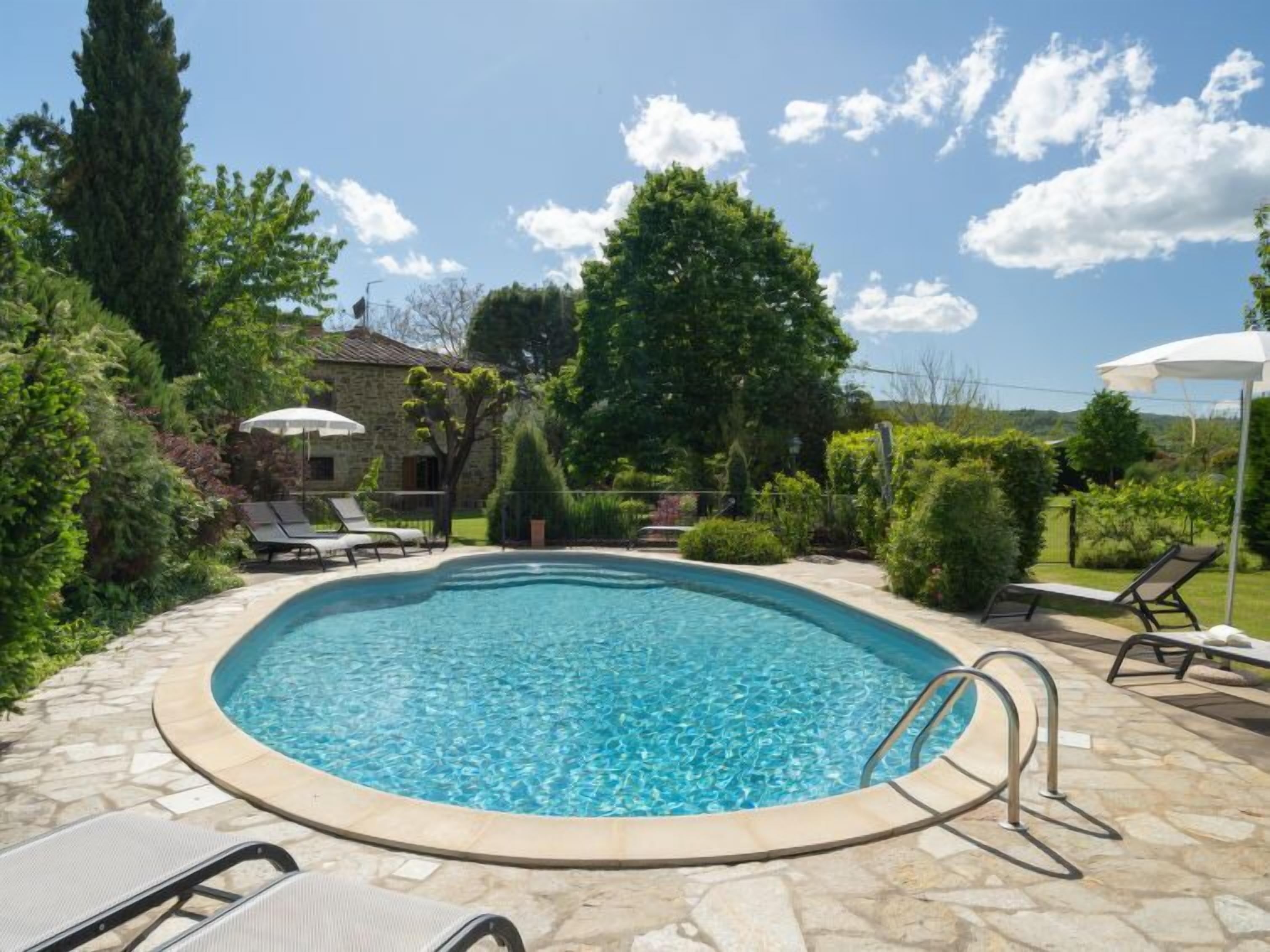 A swimming pool with lounge chairs and a stone patio.