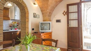 Una cucina accogliente con TV, mobili in legno e un'area pranzo con tavolo e sedie.