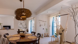 A dining area with a round wooden table, woven placemats, and a hanging light fixture. - Villa Griota by Interhome (Umag)