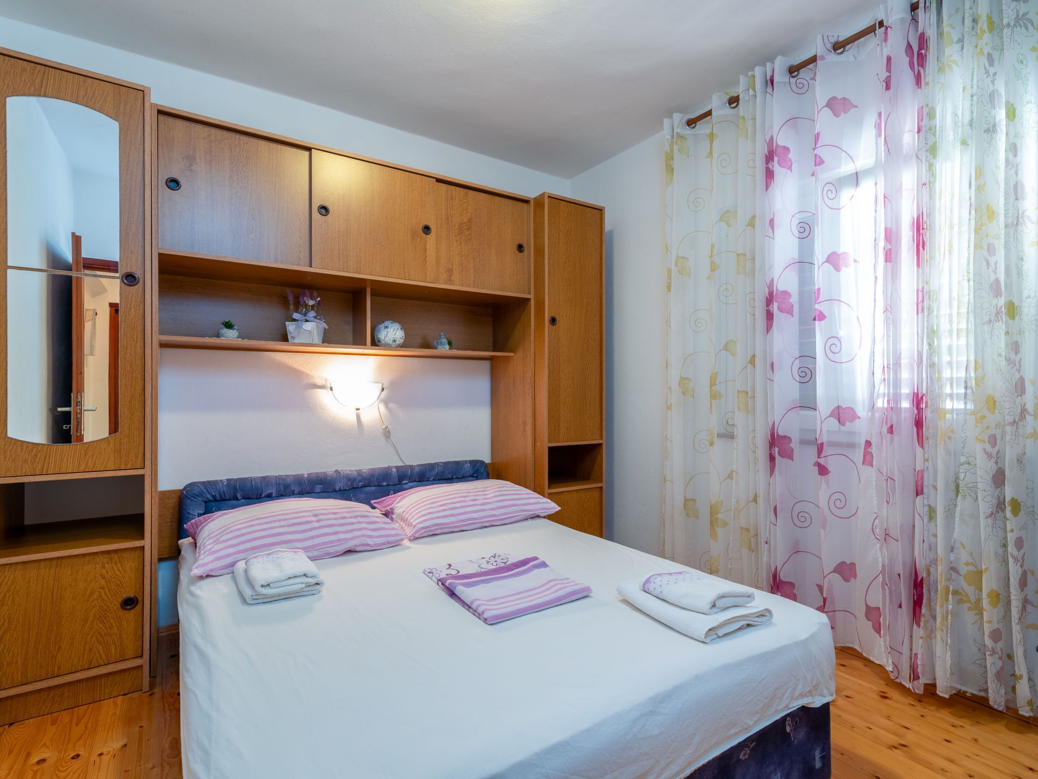 A bedroom with a bed, wooden wardrobe, and a mirror.