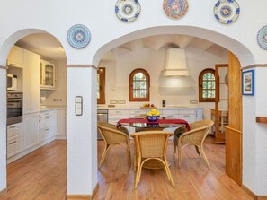 A kitchen with white cabinets, a dining table with wicker chairs, and decorative plates on the wall.