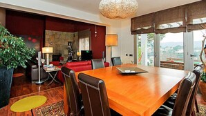 Un espace repas moderne avec une table en bois, des chaises en cuir et une grande fenêtre donnant sur l’extérieur.