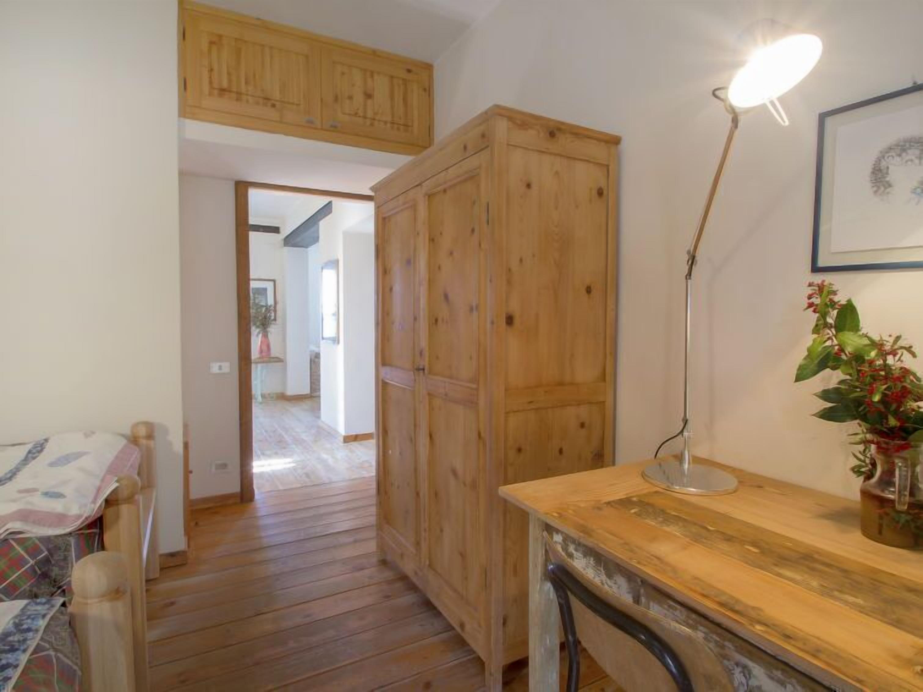 A wooden bedroom with a bed, a desk, and a cabinet.