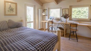 A bedroom with a bed, a desk, and two chairs. There are windows and a radiator. - Paradiso by Interhome (Perugia)