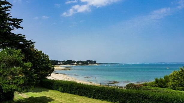 Un paisaje costero con vista despejada al mar, una playa de arena y un sendero que lleva al agua.