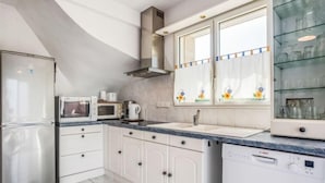Cocina moderna con armarios blancos, microondas integrado, lavavajillas y una ventana con vidrieras.