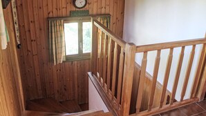 A wooden staircase with a wooden railing, a clock, and a window with curtains. - L'Alpage by Interhome (Ovronnaz)