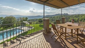 Un espacio al aire libre cubierto con piscina, una mesa y sillas, y vistas del paisaje.