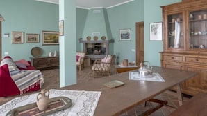 Una sala de estar acogedora con chimenea, un mueble de madera con vajilla y una mesa de comedor con tetera.
