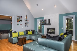 A modern living room with a sectional sofa, a fireplace, and a wall-mounted decoration.