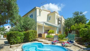Ein Poolbereich mit Whirlpool, Liegestühlen und einem Gebäude mit überdachter Terrasse.