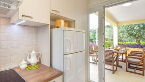 Eine moderne Küche mit Einbauherd, Kühlschrank und Essbereich inklusive Tisch und Stühlen.