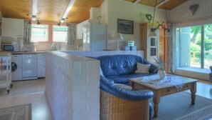 Un salon confortable avec un canapé bleu, une table basse en bois et une cuisine équipée d’un lave-linge.