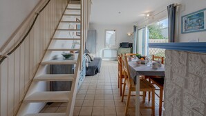 A staircase leading to a dining area with a table set for two, a television, and a view of the outdoors. - Les Jardins du Barcarès by Interhome (Le Barcarès)