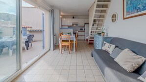 A modern apartment with a dining area, kitchen, and a living room with a sofa and a large window. - Les Jardins du Barcarès by Interhome (Le Barcarès)