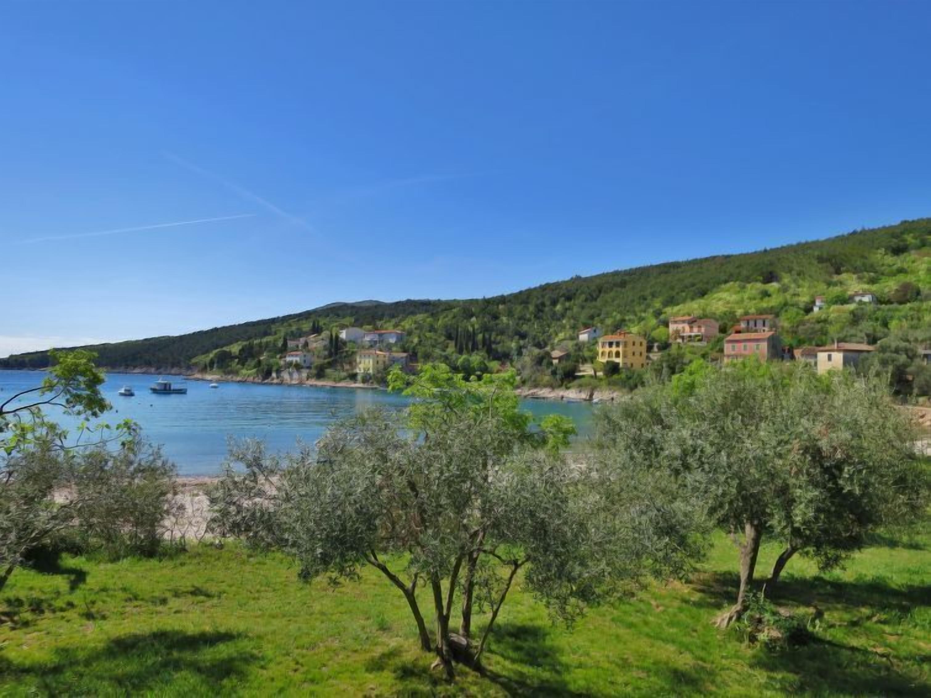 A coastal village with houses on a hillside overlooking a calm sea.