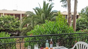 An outdoor dining table set with plates, cutlery, glasses, and a pitcher, surrounded by lush greenery and a view of buildings in the background. - Le Village by Interhome (Saint Cyr sur mer Les Lecques)