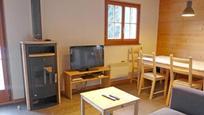 Una sala de estar acogedora con televisor, muebles de madera y una ventana.